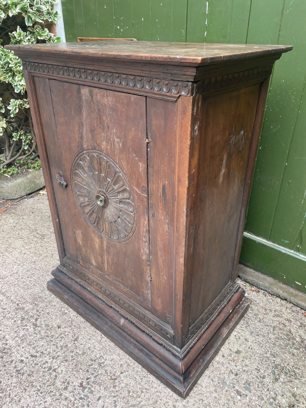 An early 18th-century Italian Tuscan walnut pedestal cupboard featuring a single cupboard door carved with a central circular rosette motif and framed by architectural moulding on a plinth base. View VII