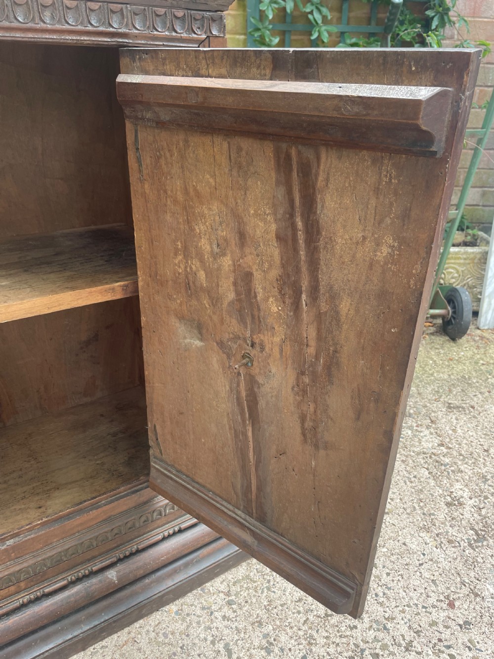 An early 18th-century Italian Tuscan walnut pedestal cupboard featuring a single cupboard door carved with a central circular rosette motif and framed by architectural moulding on a plinth base. View X
