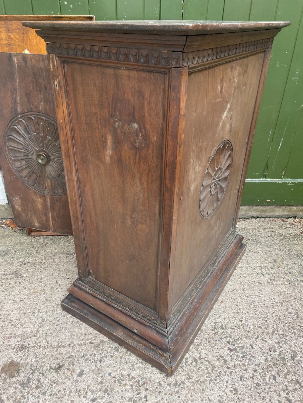 An early 18th-century Italian Tuscan walnut pedestal cupboard featuring a single cupboard door carved with a central circular rosette motif and framed by architectural moulding on a plinth base. View XI