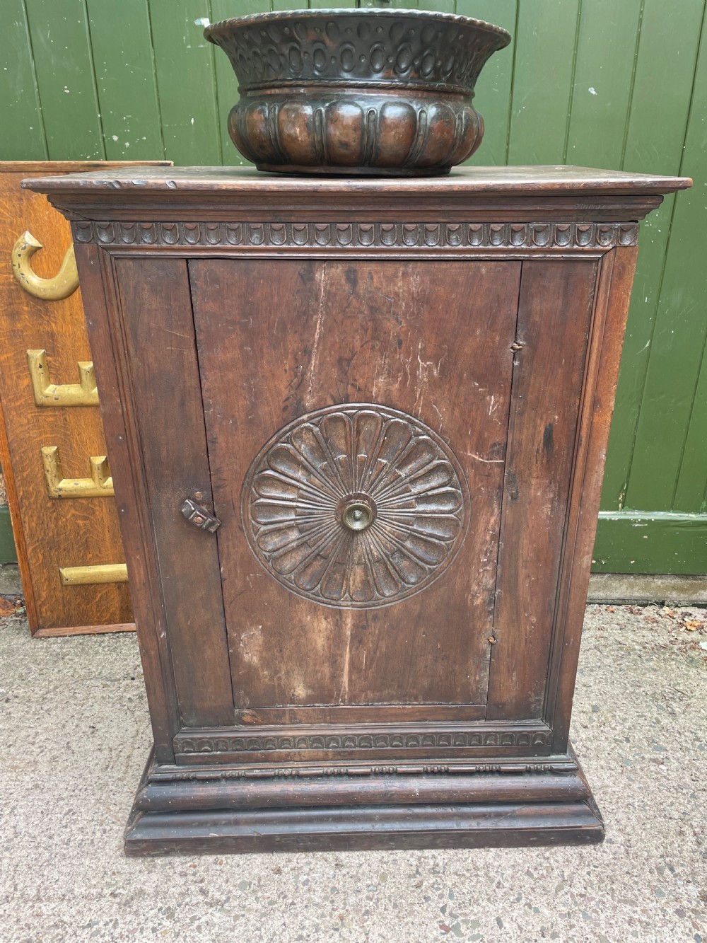 An early 18th-century Italian Tuscan walnut pedestal cupboard featuring a single cupboard door carved with a central circular rosette motif and framed by architectural moulding on a plinth base. View XVIII