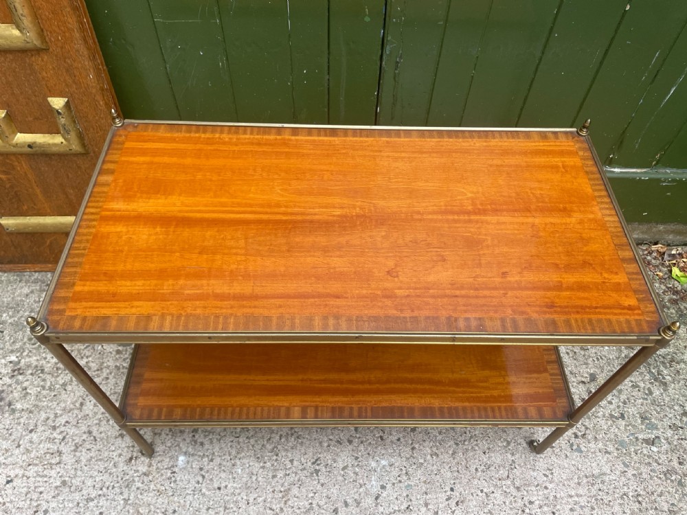 A low rectangular two-tier etagere table featuring satinwood shelves with decorative crossbanded inlay and a brass frame on castors. View III
