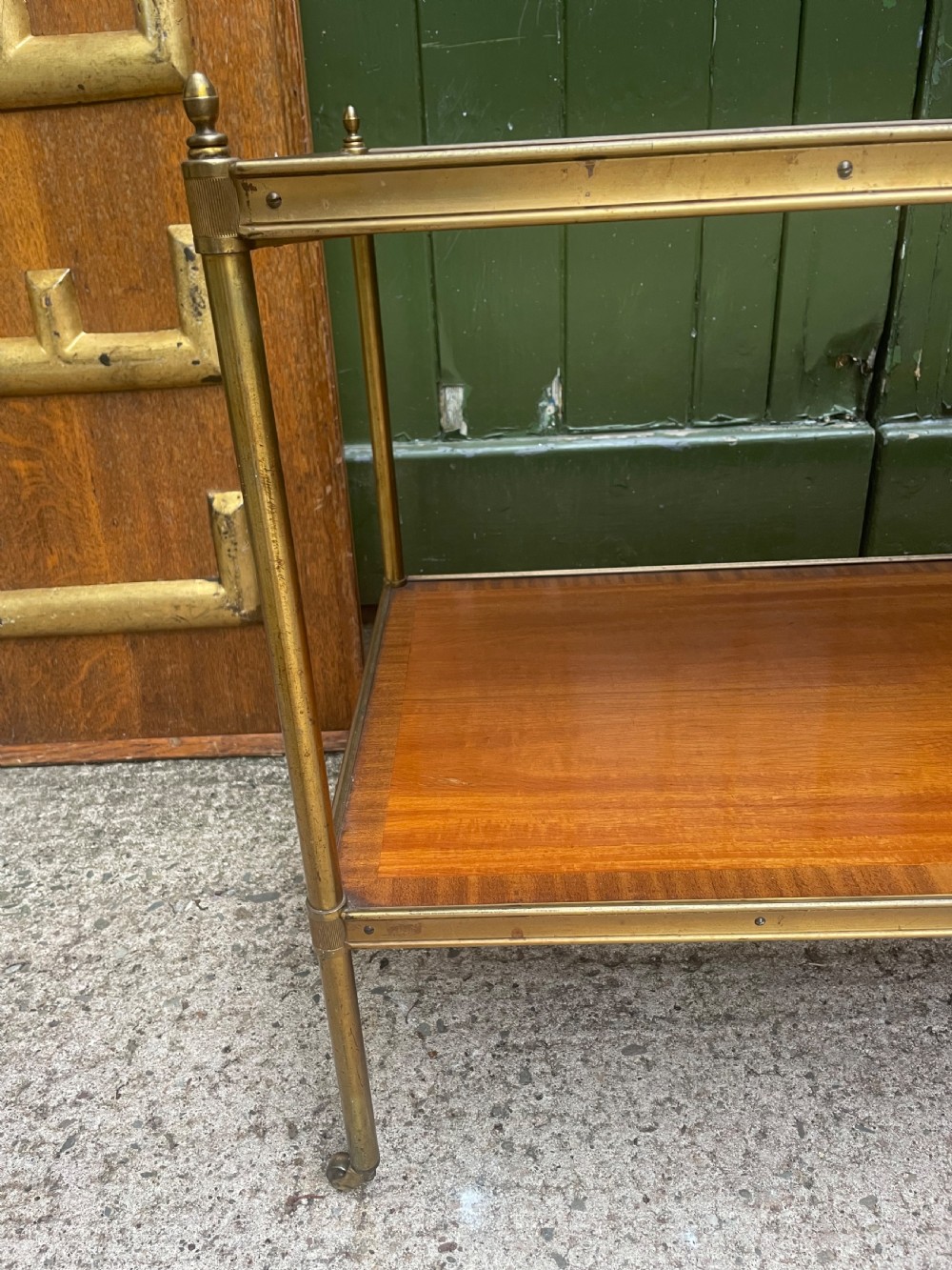 A low rectangular two-tier etagere table featuring satinwood shelves with decorative crossbanded inlay and a brass frame on castors. View V