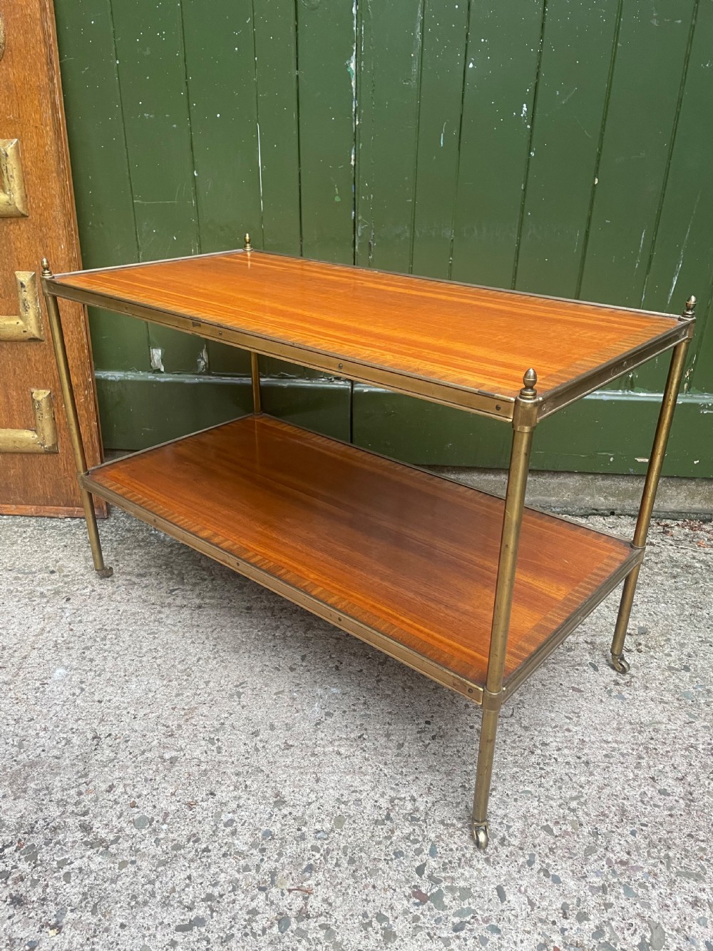 A low rectangular two-tier etagere table featuring satinwood shelves with decorative crossbanded inlay and a brass frame on castors. View IX