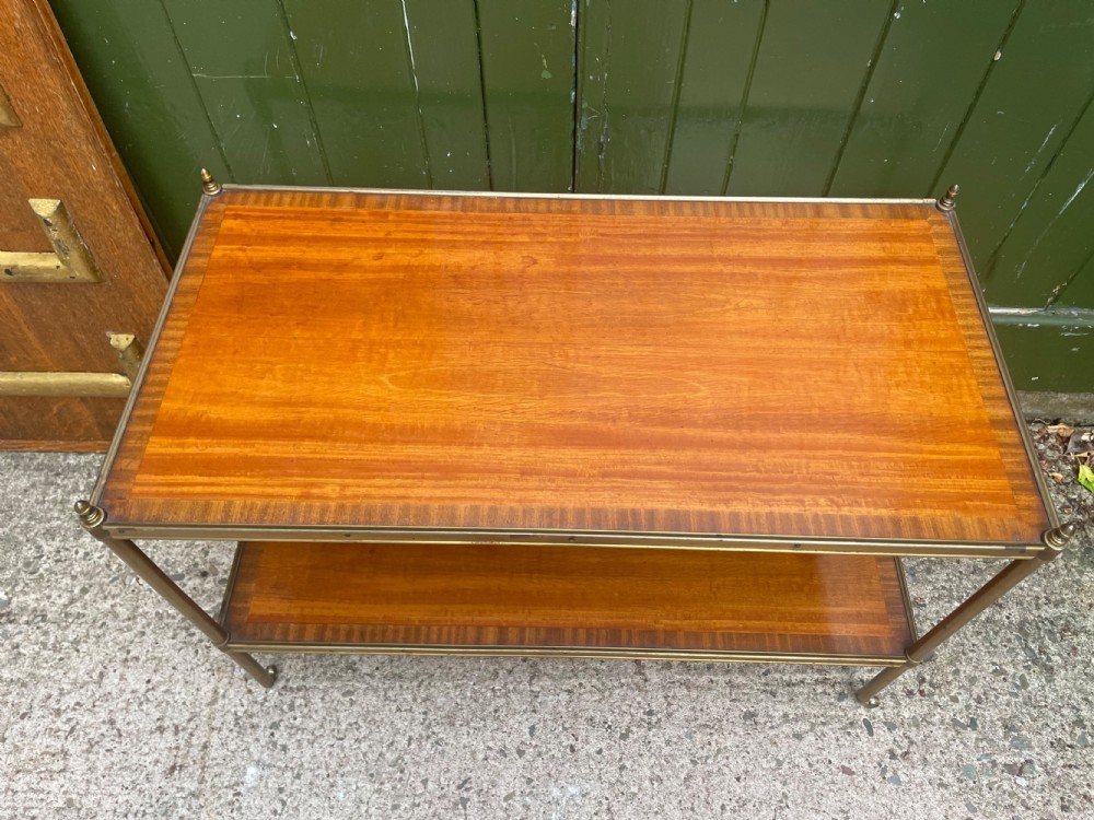 A low rectangular two-tier etagere table featuring satinwood shelves with decorative crossbanded inlay and a brass frame on castors. View XII