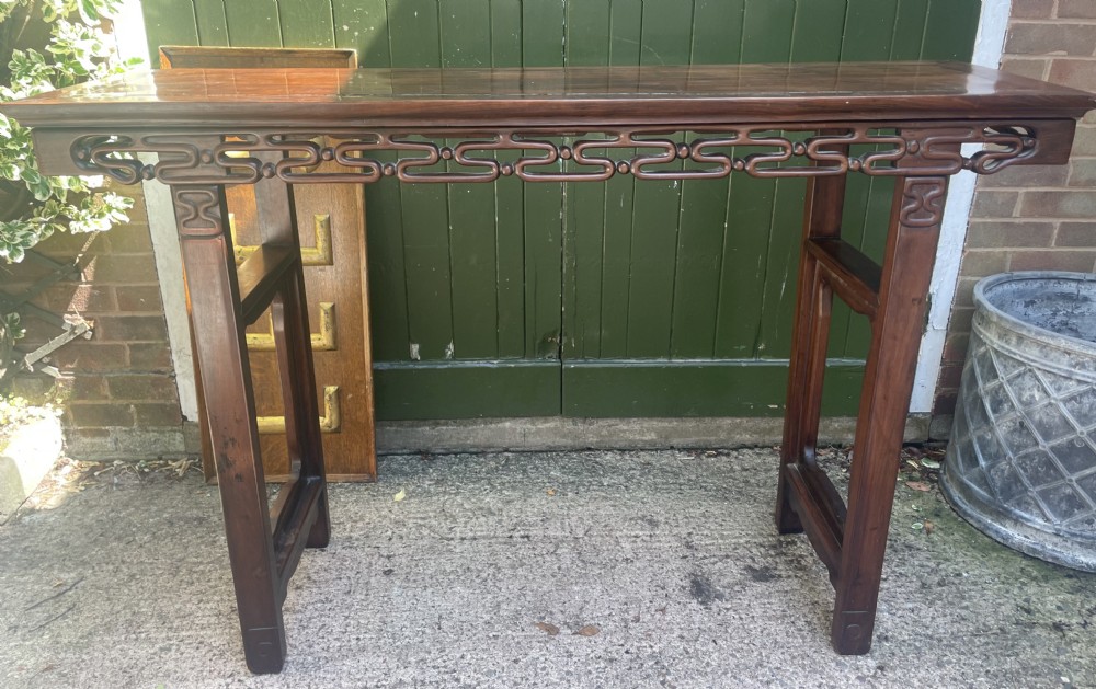 A late nineteenth-century Chinese carved hardwood altar table with an openwork apron and straight legs.