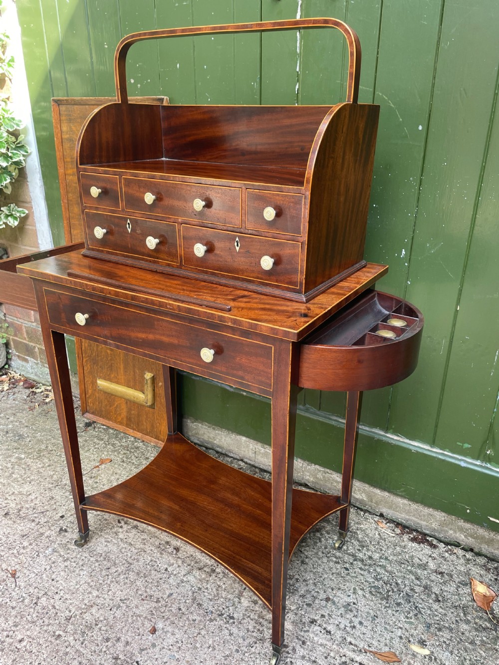 A late 18th-century George III Sheraton mahogany cheveret writing desk featuring a removable upper drawer section with an arched handle, line inlay, and tapered square legs on castors. View II