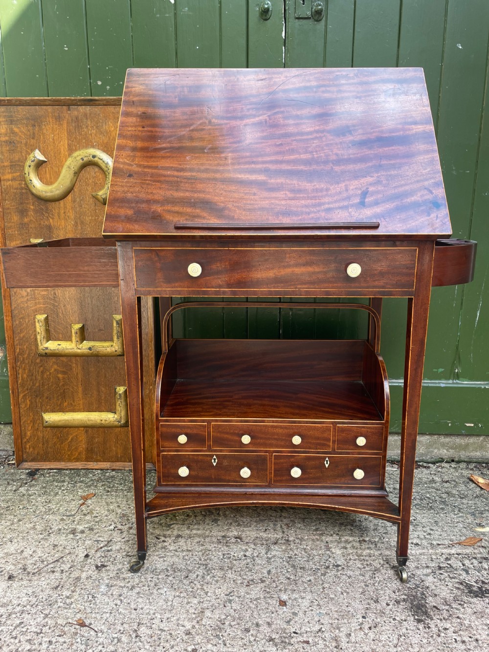 A late 18th-century George III Sheraton mahogany cheveret writing desk featuring a removable upper drawer section with an arched handle, line inlay, and tapered square legs on castors. View V
