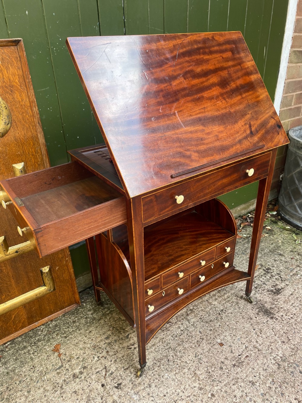 A late 18th-century George III Sheraton mahogany cheveret writing desk featuring a removable upper drawer section with an arched handle, line inlay, and tapered square legs on castors. View VI