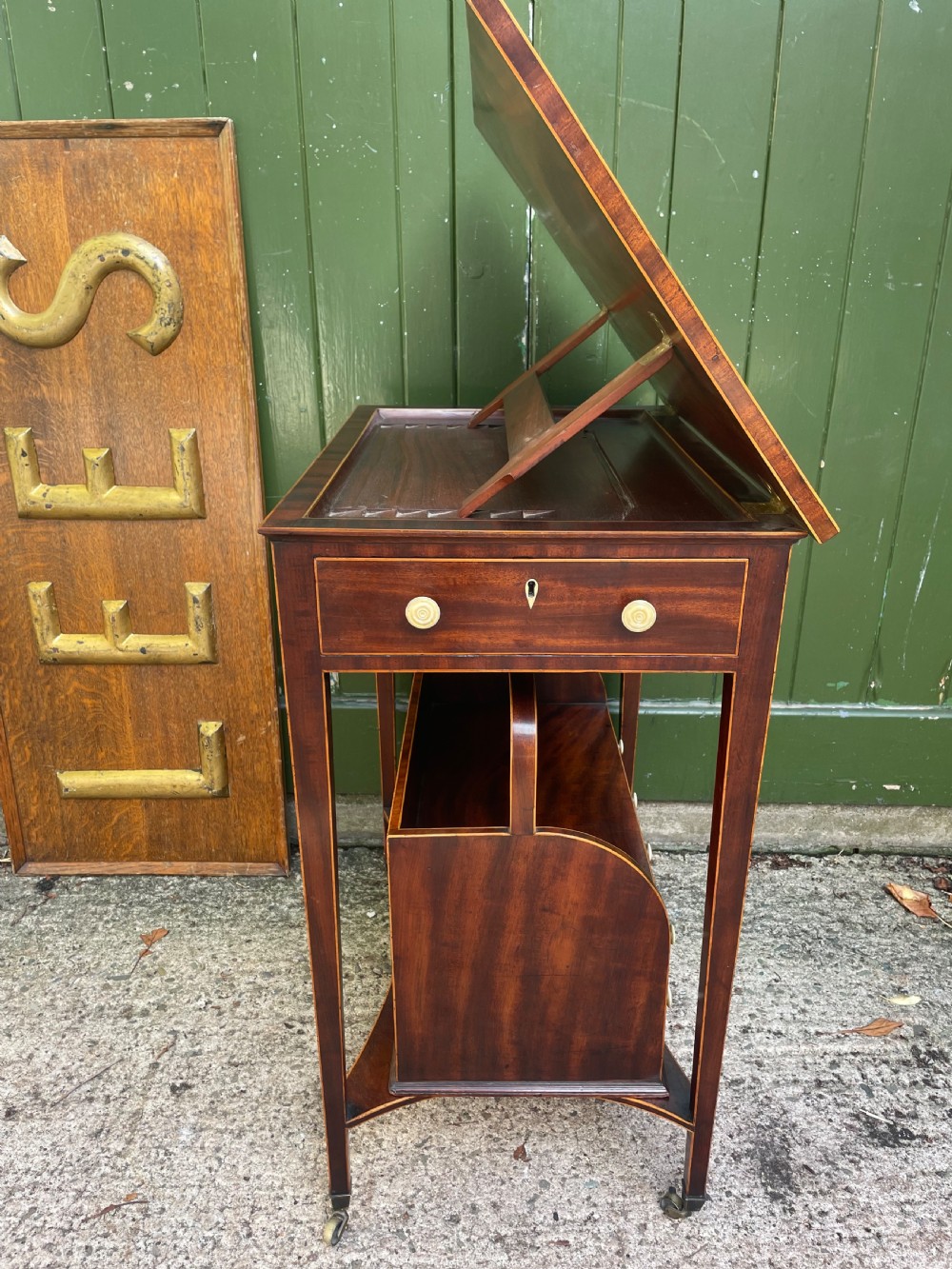 A late 18th-century George III Sheraton mahogany cheveret writing desk featuring a removable upper drawer section with an arched handle, line inlay, and tapered square legs on castors. View X