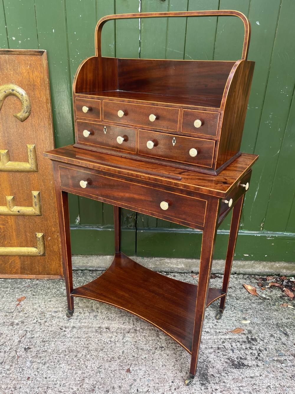 A late 18th-century George III Sheraton mahogany cheveret writing desk featuring a removable upper drawer section with an arched handle, line inlay, and tapered square legs on castors. View XIII