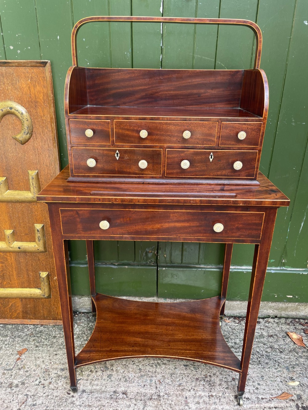 A late 18th-century George III Sheraton mahogany cheveret writing desk featuring a removable upper drawer section with an arched handle, line inlay, and tapered square legs on castors. View XV