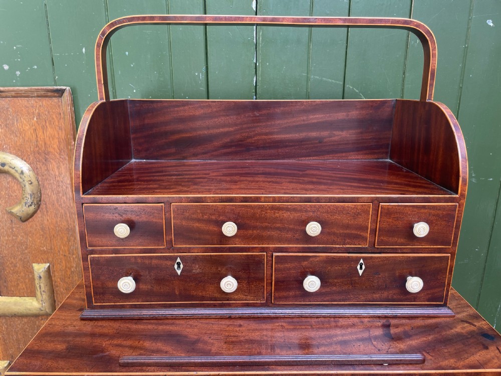 A late 18th-century George III Sheraton mahogany cheveret writing desk featuring a removable upper drawer section with an arched handle, line inlay, and tapered square legs on castors. View XVII