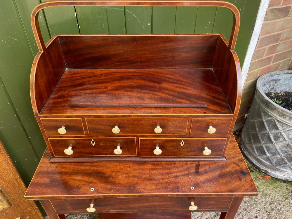 A late 18th-century George III Sheraton mahogany cheveret writing desk featuring a removable upper drawer section with an arched handle, line inlay, and tapered square legs on castors. View XVIII