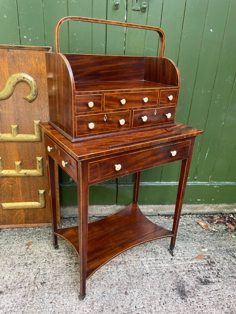A late 18th-century George III Sheraton mahogany cheveret writing desk featuring a removable upper drawer section with an arched handle, line inlay, and tapered square legs on castors. View XX