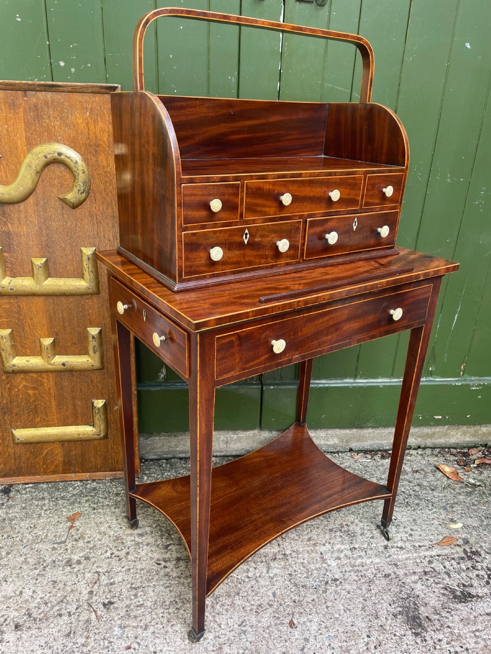 A late 18th-century George III Sheraton mahogany cheveret writing desk featuring a removable upper drawer section with an arched handle, line inlay, and tapered square legs on castors. View XXI