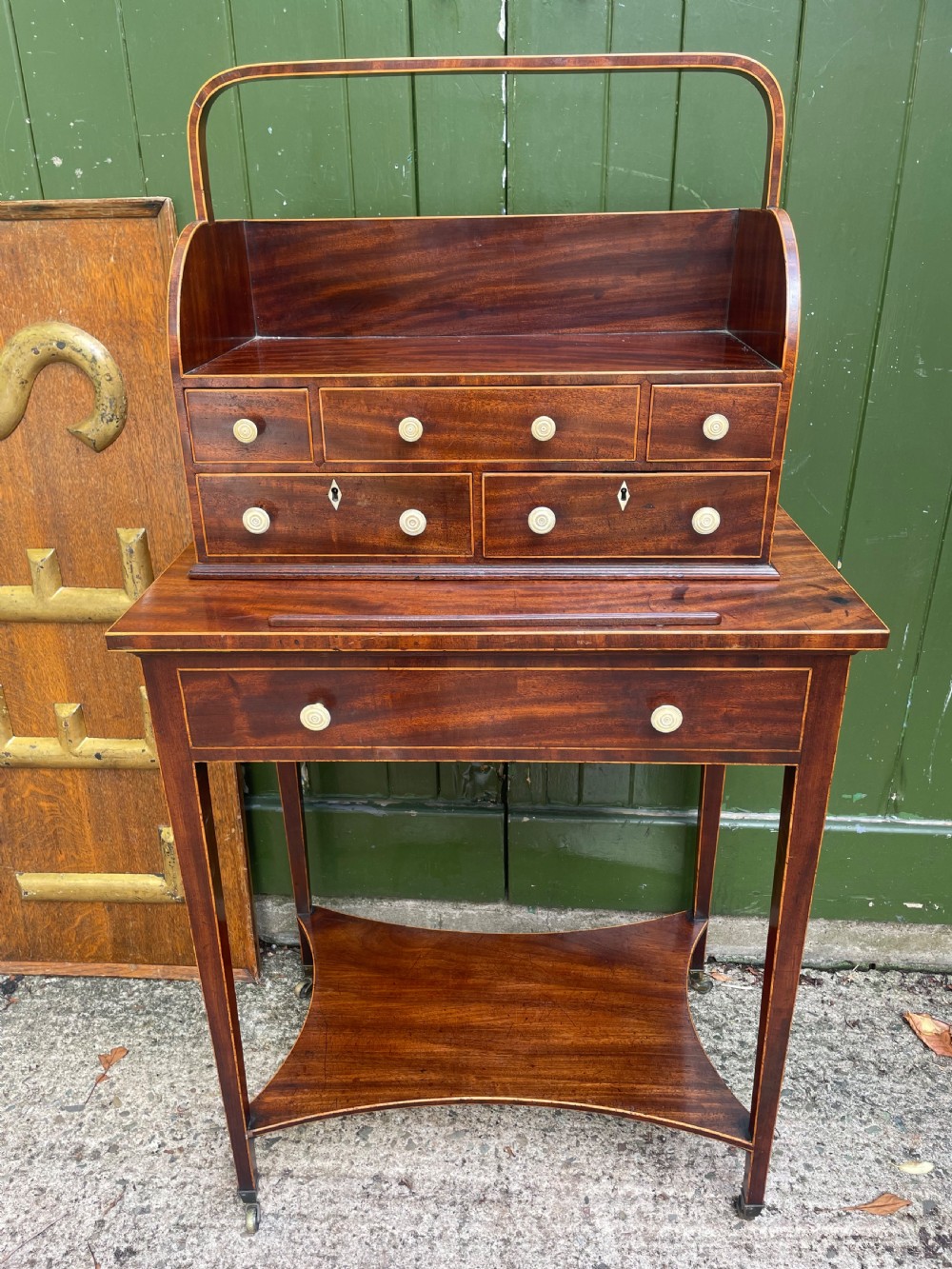 A late 18th-century George III Sheraton mahogany cheveret writing desk featuring a removable upper drawer section with an arched handle, line inlay, and tapered square legs on castors. View XXIV