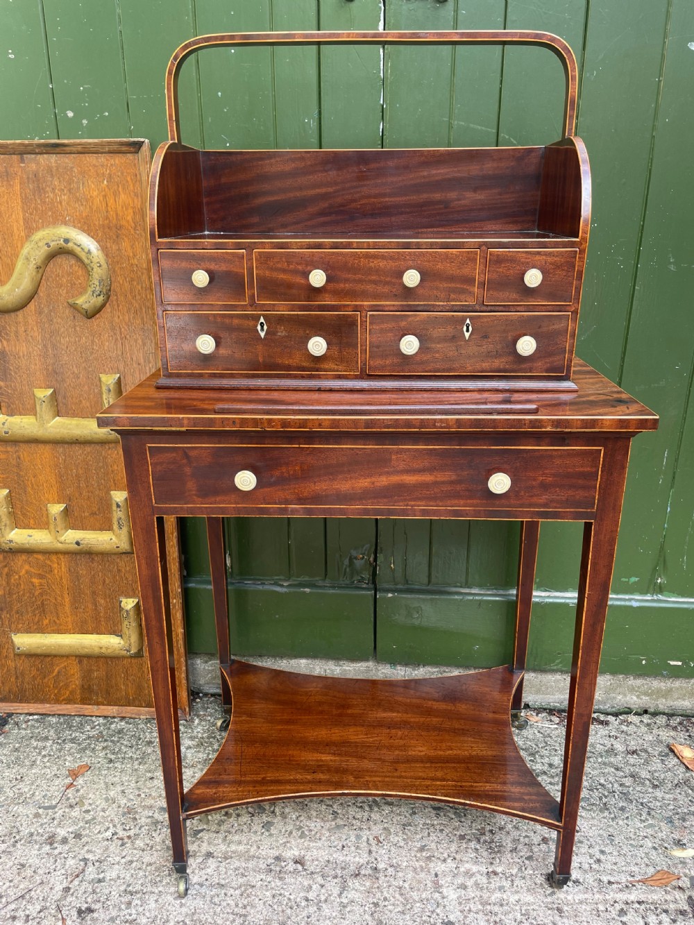 A late 18th-century George III Sheraton mahogany cheveret writing desk featuring a removable upper drawer section with an arched handle, line inlay, and tapered square legs on castors. View XXV