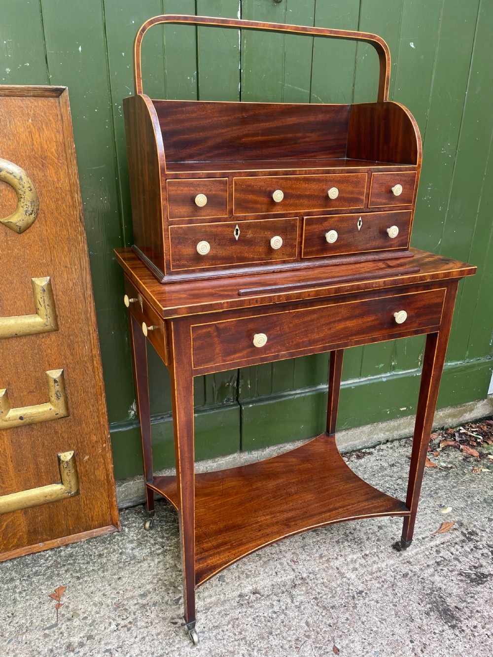 A late 18th-century George III Sheraton mahogany cheveret writing desk featuring a removable upper drawer section with an arched handle, line inlay, and tapered square legs on castors. View XXVI
