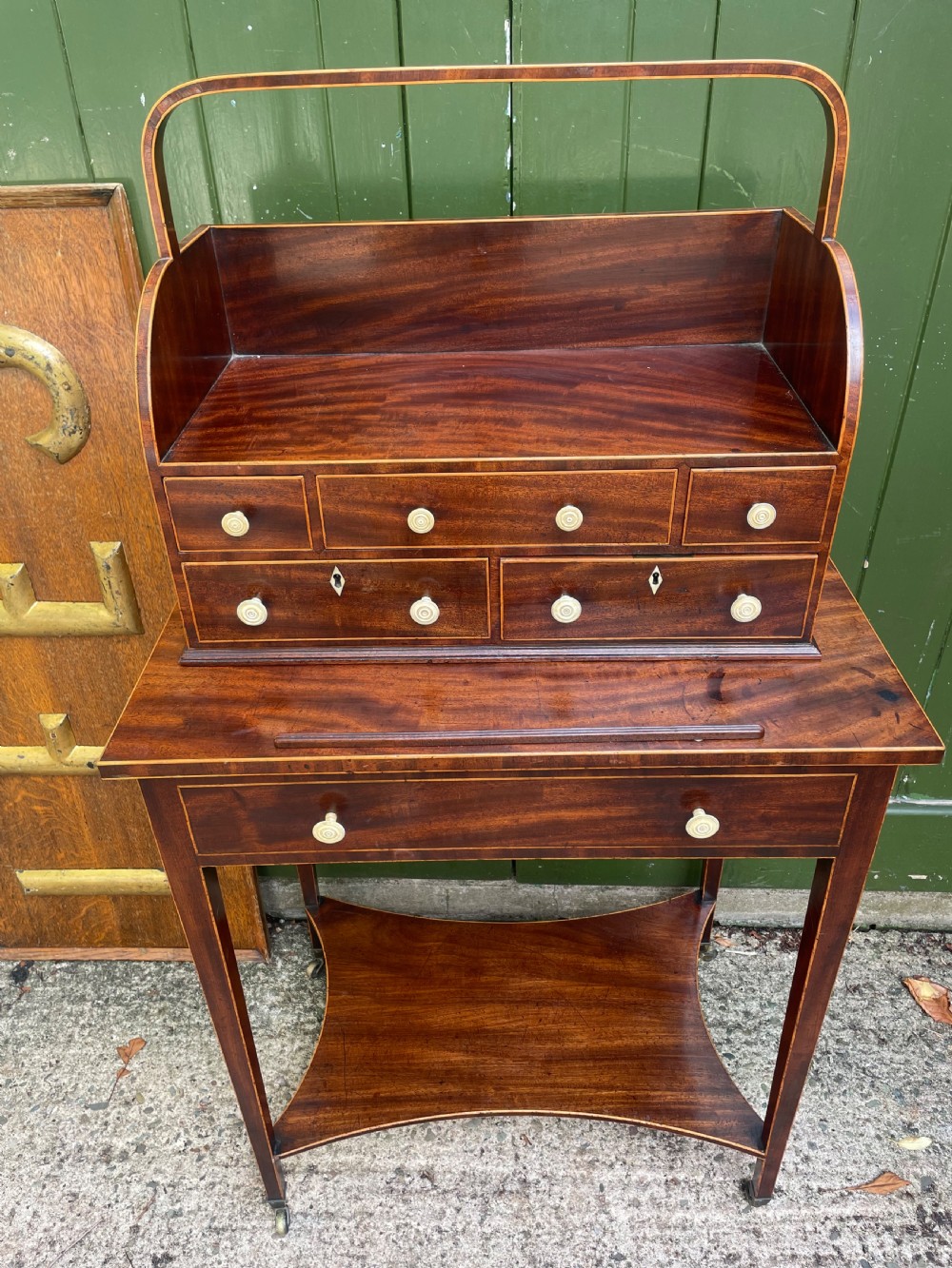 A late 18th-century George III Sheraton mahogany cheveret writing desk featuring a removable upper drawer section with an arched handle, line inlay, and tapered square legs on castors. View XXVII