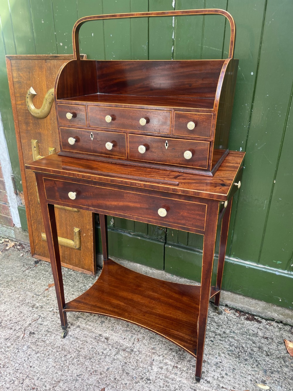 A late 18th-century George III Sheraton mahogany cheveret writing desk featuring a removable upper drawer section with an arched handle, line inlay, and tapered square legs on castors. View XXVIII