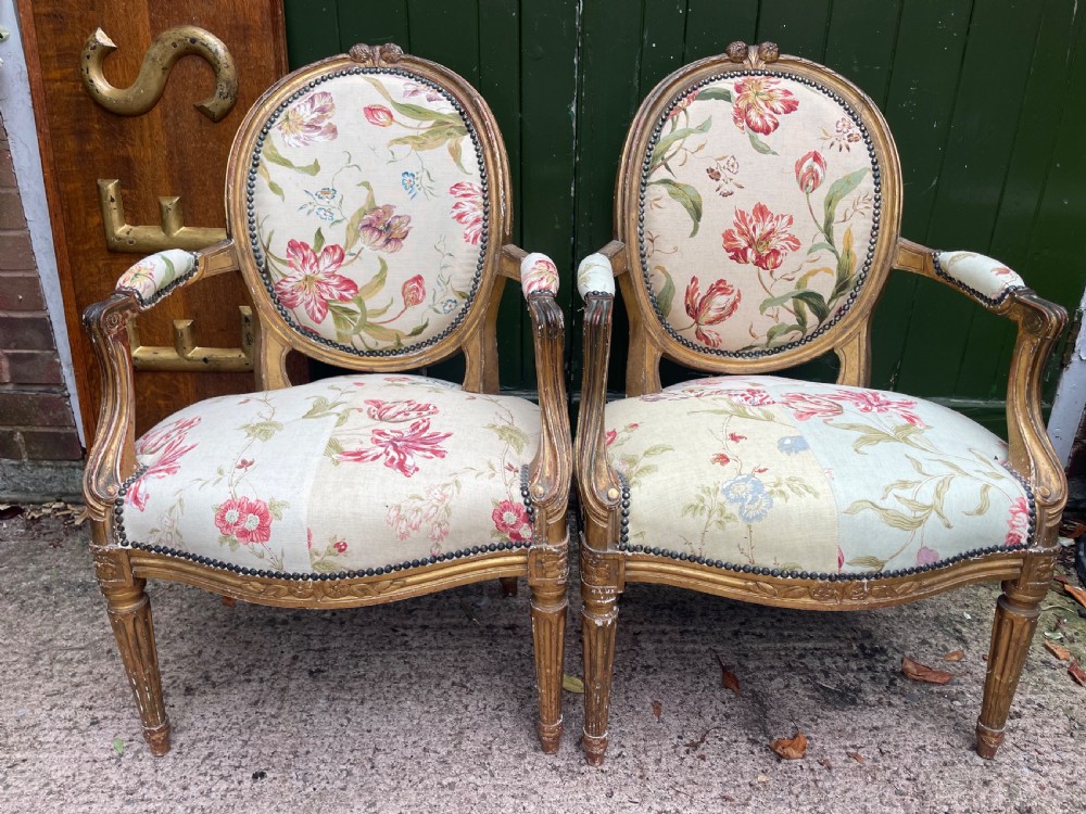 A pair of mid-19th-century French Louis XVI style giltwood salon armchairs with oval backs and floral upholstery. View II