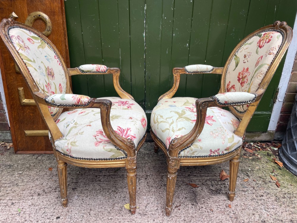 A pair of mid-19th-century French Louis XVI style giltwood salon armchairs with oval backs and floral upholstery. View XIII