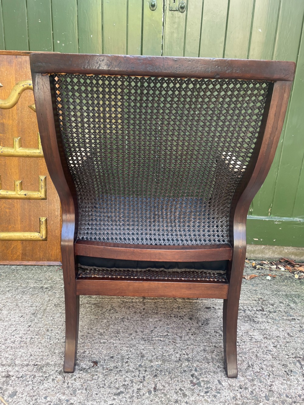 An early 19th-century Regency mahogany bergere armchair with woven cane back and sides, curved armrests, and a dark squab cushion. View VIII