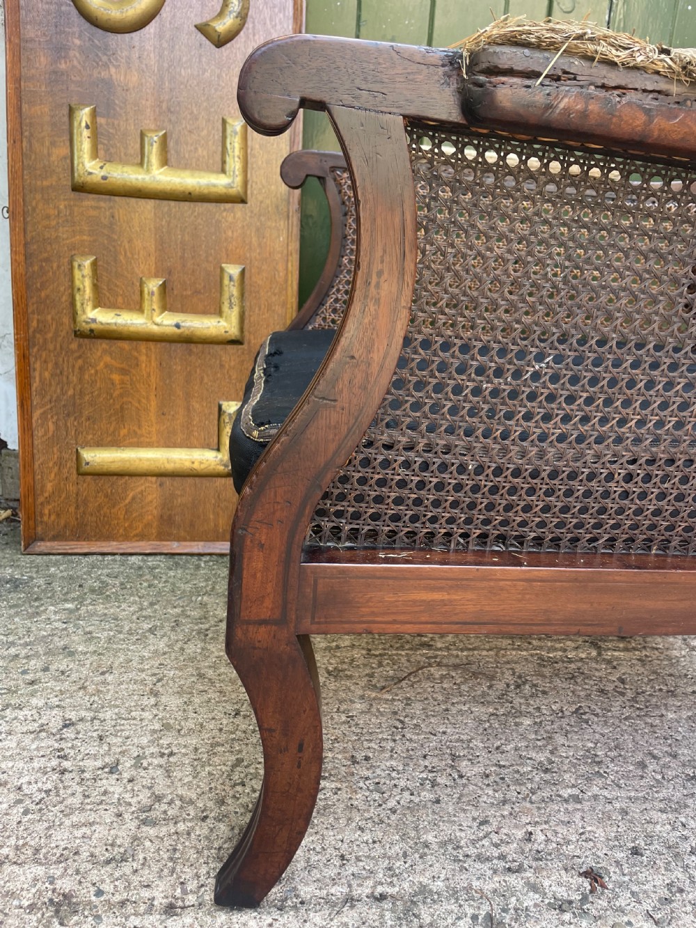 An early 19th-century Regency mahogany bergere armchair with woven cane back and sides, curved armrests, and a dark squab cushion. View XIII