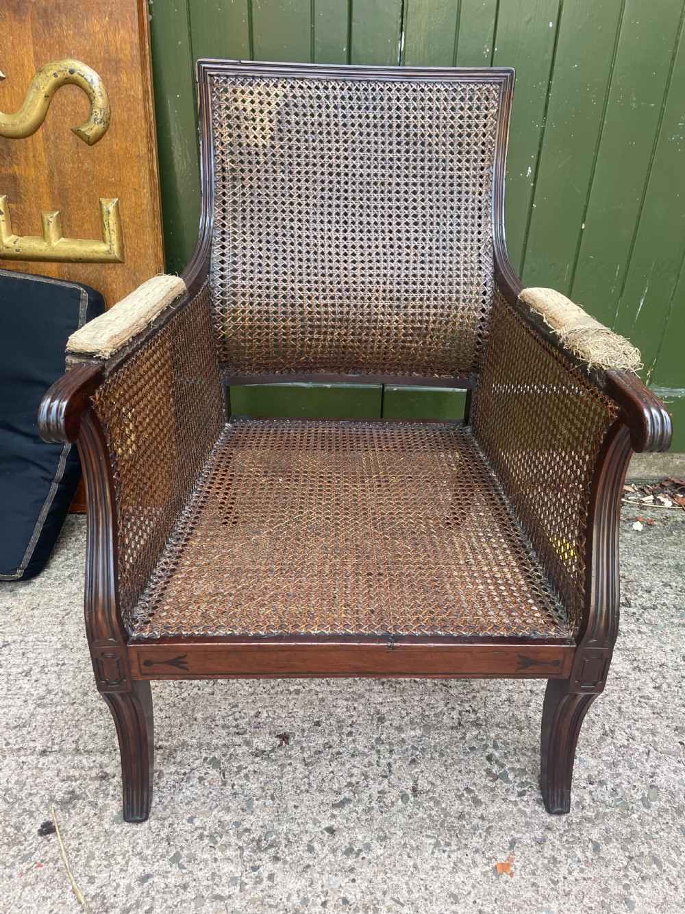 An early 19th-century Regency mahogany bergere armchair with woven cane back and sides, curved armrests, and a dark squab cushion. View XIV