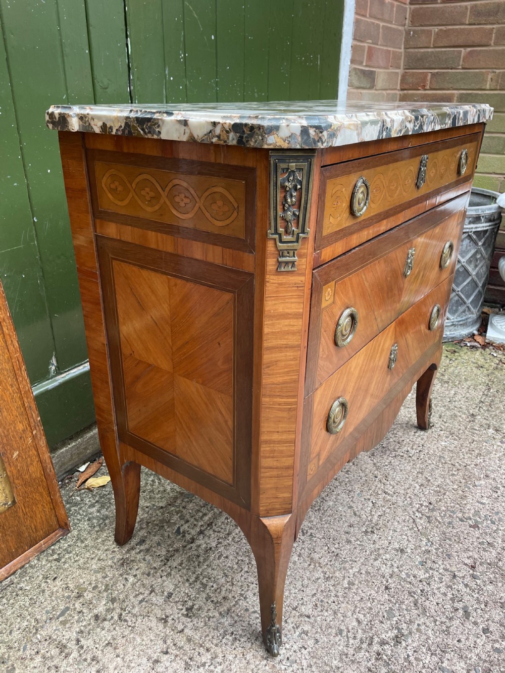 A late nineteenth-century French Louis XVI transitional style commode featuring marquetry wood veneers, brass ring handles, and a grey marble top. View V