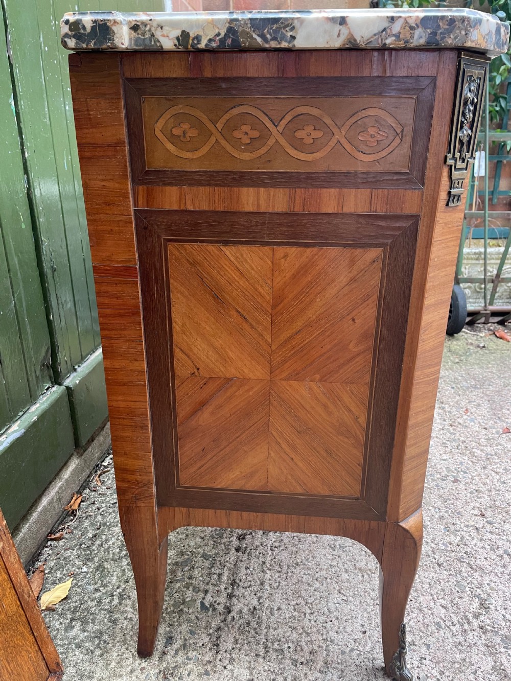 A late nineteenth-century French Louis XVI transitional style commode featuring marquetry wood veneers, brass ring handles, and a grey marble top. View VI