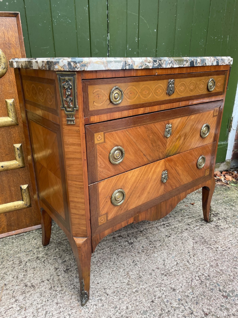 A late nineteenth-century French Louis XVI transitional style commode featuring marquetry wood veneers, brass ring handles, and a grey marble top. View XIV