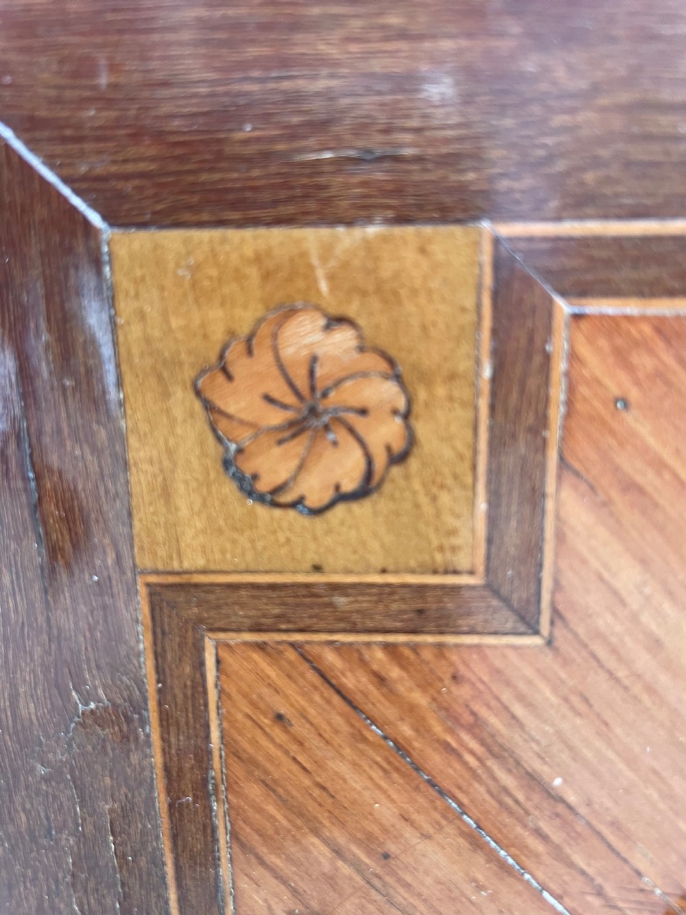 A late nineteenth-century French Louis XVI transitional style commode featuring marquetry wood veneers, brass ring handles, and a grey marble top. View XVII