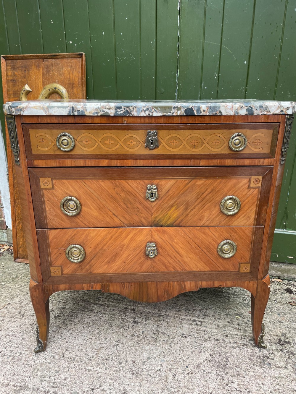 A late nineteenth-century French Louis XVI transitional style commode featuring marquetry wood veneers, brass ring handles, and a grey marble top. View XIX