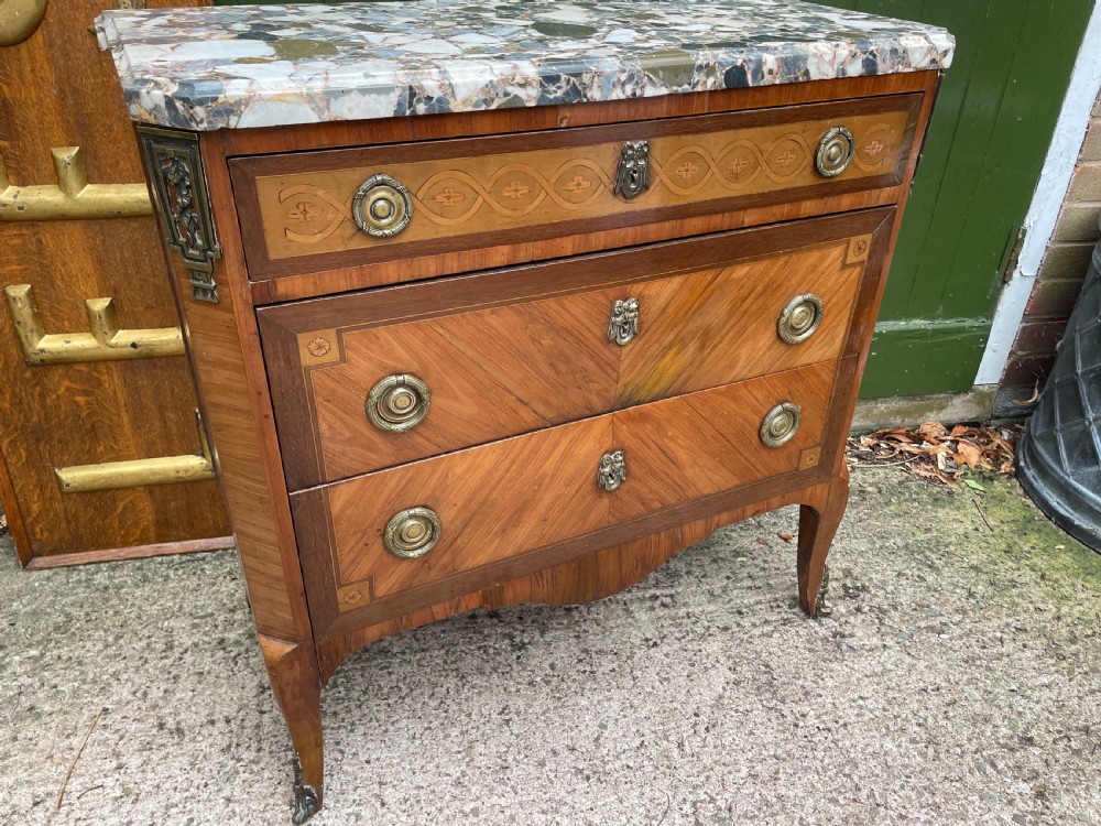 A late nineteenth-century French Louis XVI transitional style commode featuring marquetry wood veneers, brass ring handles, and a grey marble top. View XX