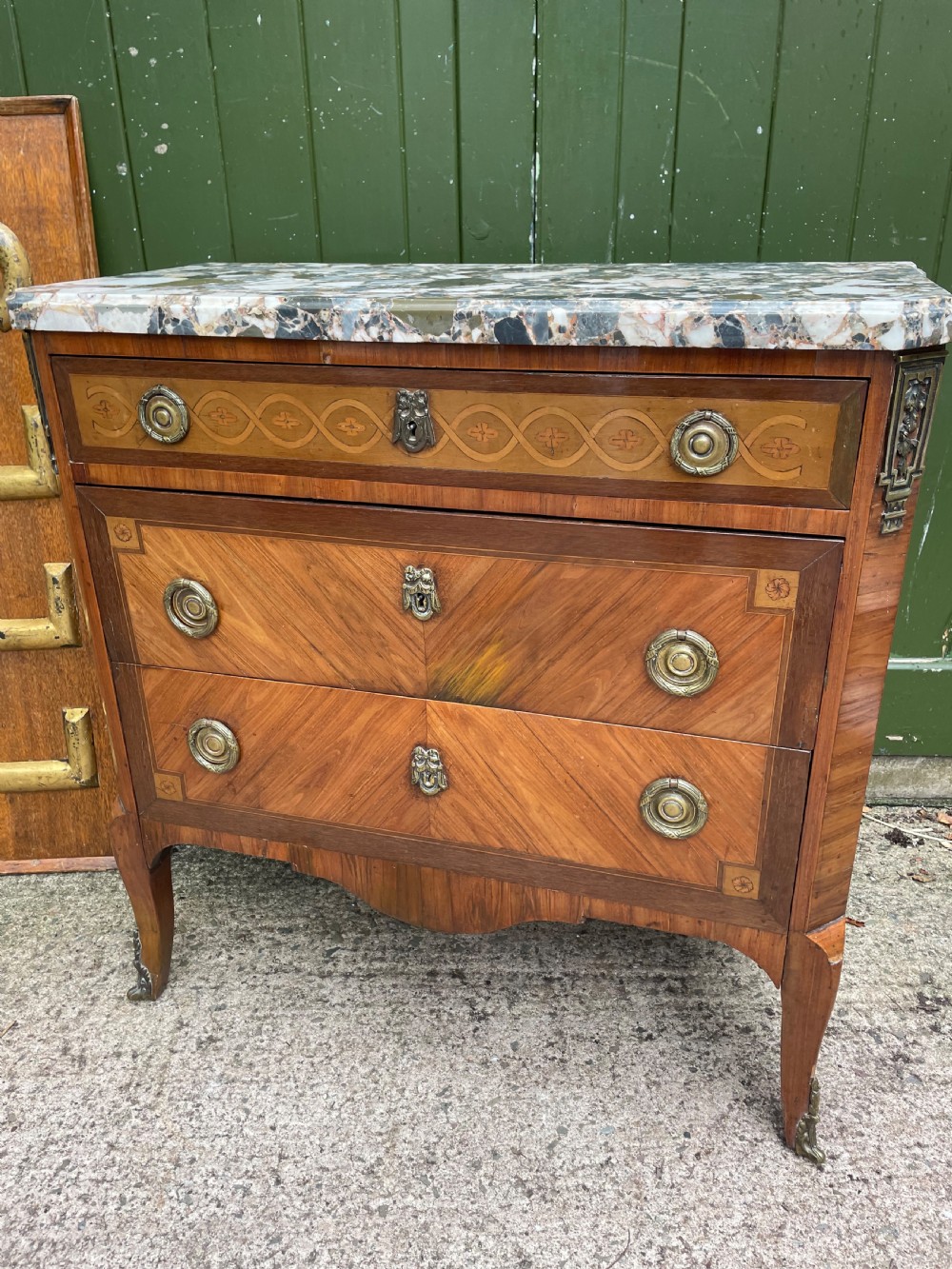 A late nineteenth-century French Louis XVI transitional style commode featuring marquetry wood veneers, brass ring handles, and a grey marble top. View XXVI