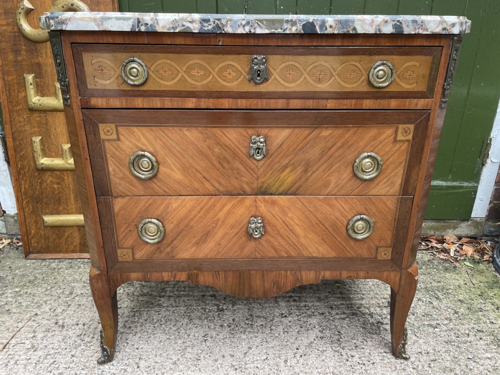 A late nineteenth-century French Louis XVI transitional style commode featuring marquetry wood veneers, brass ring handles, and a grey marble top. View XXVIII