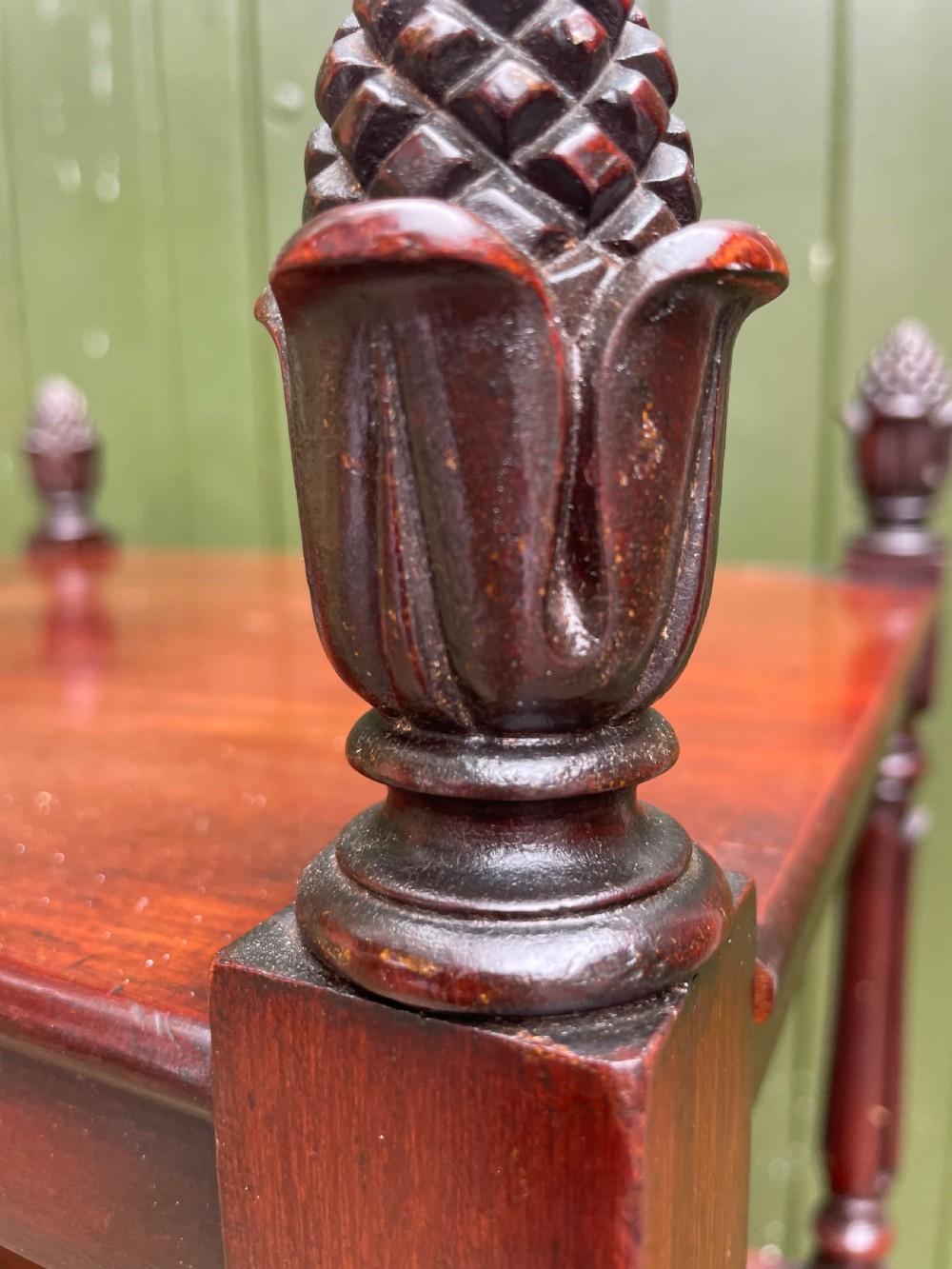 An early nineteenth-century George IV mahogany four-tier etagere featuring carved pinecone finials, turned supports, a single lower drawer, and brass castors. View III