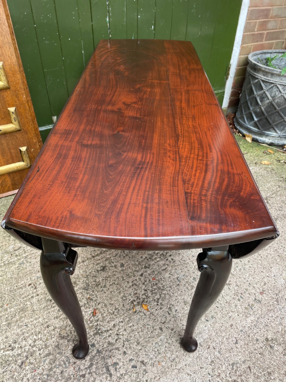 A mid-18th century George II Cuban mahogany drop-leaf table featuring an oval top, cabriole legs, and pad feet. View III