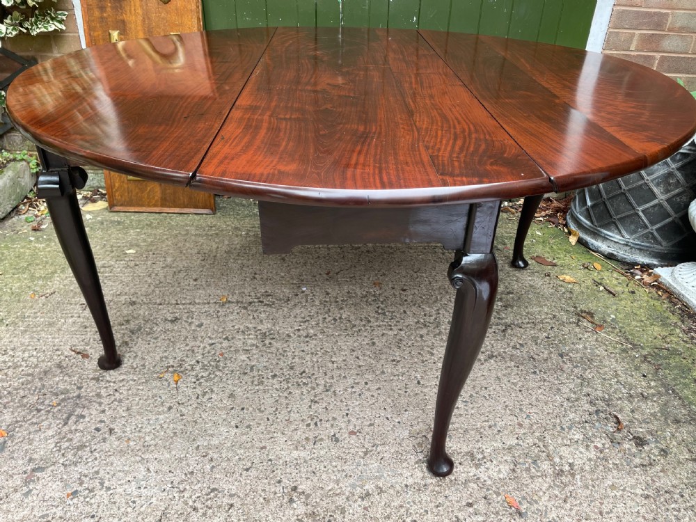 A mid-18th century George II Cuban mahogany drop-leaf table featuring an oval top, cabriole legs, and pad feet. View XVI