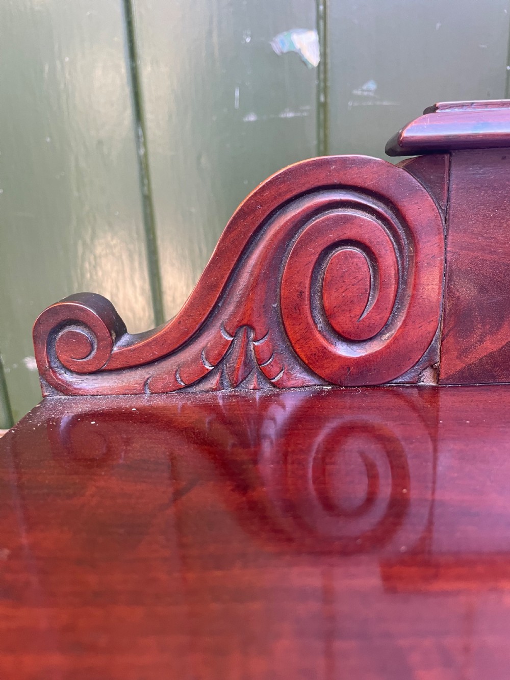 An early nineteenth-century George IV flame mahogany chiffonier featuring a raised shelf gallery with scroll supports above a two-door cabinet supported on turned bun feet. View III