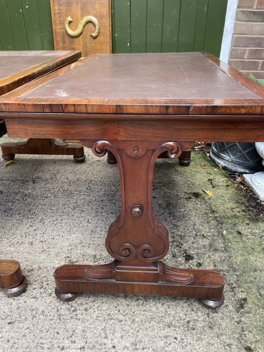 A pair of early nineteenth-century George IV rosewood library tables featuring brown leather writing surfaces, carved scroll end supports, and turned stretchers. View XII
