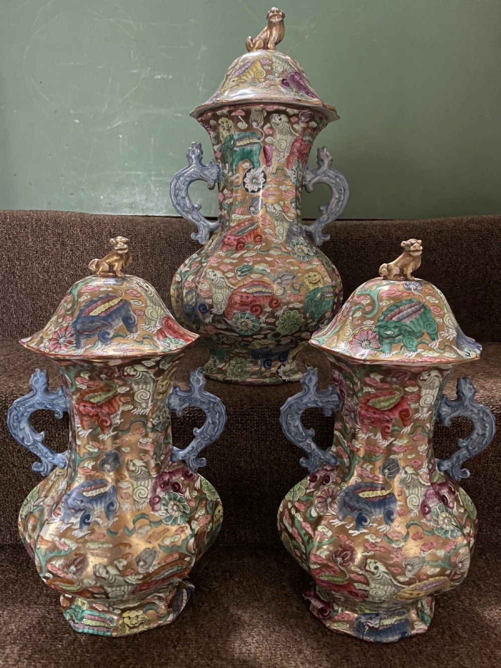 A three-piece nineteenth-century Masons Ironstone garniture set decorated with Chinoiserie enamel patterns, blue handles, and lion lid finials. View XIX