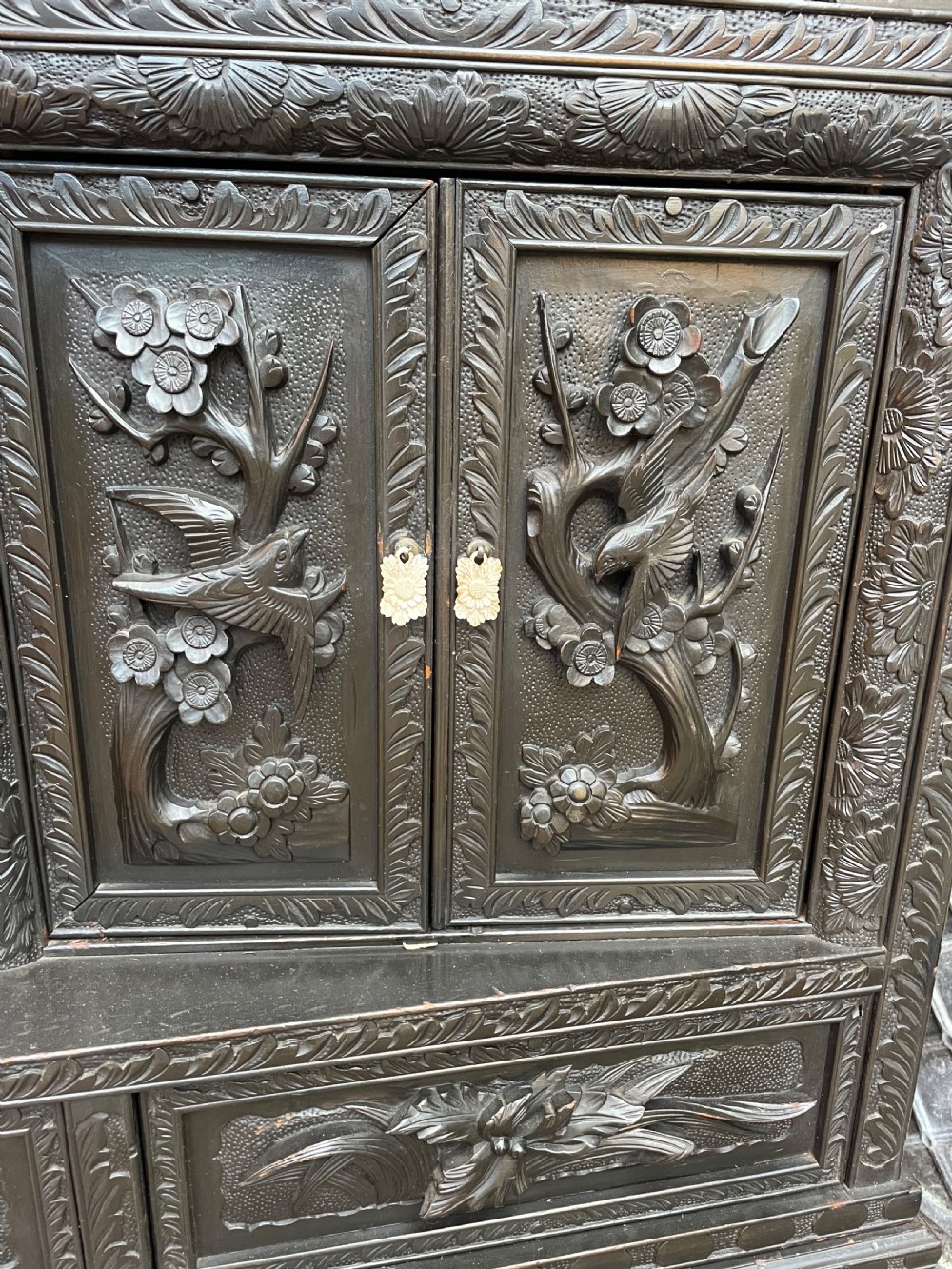 An early 20th-century Japanese ebonised timber shodana display cabinet featuring detailed dragon and floral relief carvings, asymmetrical shelving, small cupboard doors, and a carved stand base. View VIII
