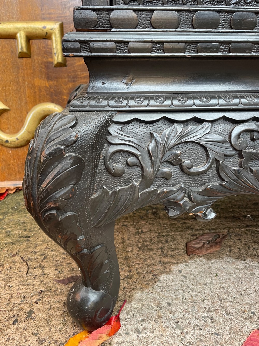 An early 20th-century Japanese ebonised timber shodana display cabinet featuring detailed dragon and floral relief carvings, asymmetrical shelving, small cupboard doors, and a carved stand base. View X