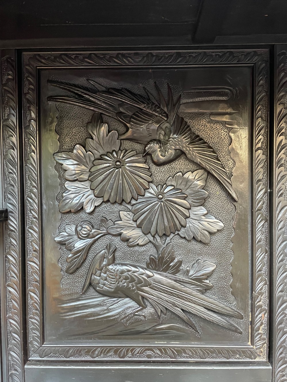 An early 20th-century Japanese ebonised timber shodana display cabinet featuring detailed dragon and floral relief carvings, asymmetrical shelving, small cupboard doors, and a carved stand base. View XI