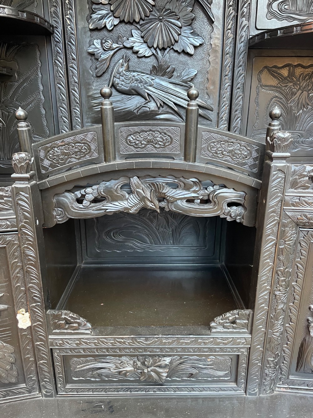 An early 20th-century Japanese ebonised timber shodana display cabinet featuring detailed dragon and floral relief carvings, asymmetrical shelving, small cupboard doors, and a carved stand base. View XXIII