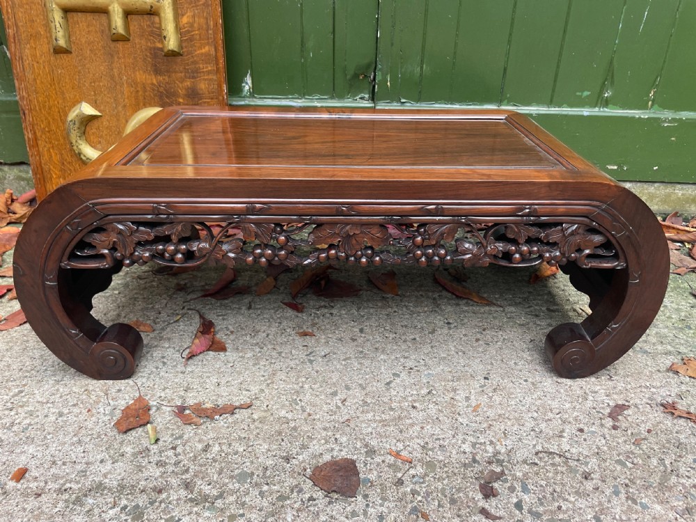 A low Chinese huali wood kang table featuring an openwork carved apron and scroll-end legs. View XI