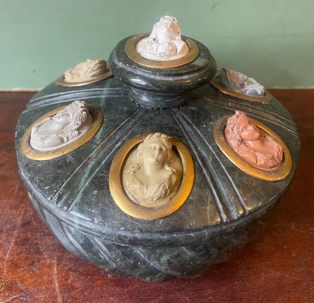 A circular dark green carved Prato Verde marble inkstand with fluted sides, set with six oval carved Vesuvian lava portrait cameos framed in brass mounts around a central raised finial. View III