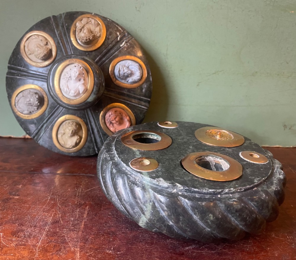 A circular dark green carved Prato Verde marble inkstand with fluted sides, set with six oval carved Vesuvian lava portrait cameos framed in brass mounts around a central raised finial. View V